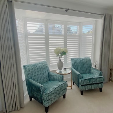Bay shutters dressed with curtains